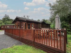 a wooden cabin with a fence and an umbrella at Langdale Lodge 15 in Windermere