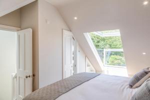 a white bedroom with a bed and a window at Cranford in Salcombe