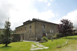 an old stone building in a field with grass at Apartamentos A Retoral in Coaña +11 photos