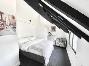 a white bedroom with a bed and a chair at 53 Church Street in Warrington