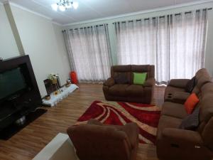 a living room with two chairs and a flat screen tv at Liyoli Guesthouse in Mthatha