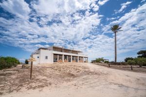 a building on a dirt road with a palm tree at Cas Saliners - Ses Illetes in La Savina