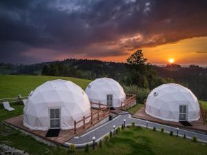 three domes in a field with the sunset in the background at Bukowina Glamp - Janiołów Wierch in Zakopane