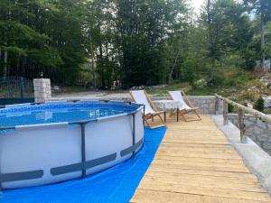 a hot tub on a deck with chairs and a table at Mountain house Ivanova Korita in Cetinje