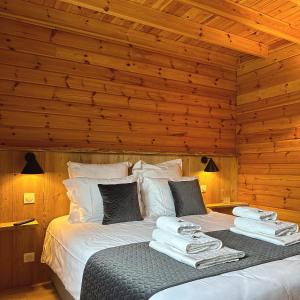 uma cama num quarto de madeira com toalhas em Chalet Le Familial - SPA & SAUNA - Serviettes - Peignoirs - Lits faits - Ménage inclus em Rochesson