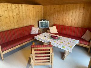 a living room with red couches and a table and a tv at Midttun Camping og Feriehytter in Vossestrand