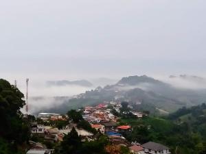 a town on a hill with fog in the background at Baan Ruam Cha in Mae Salong