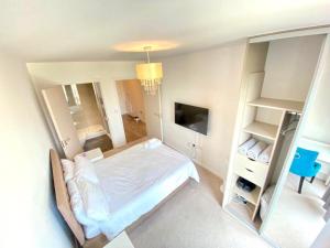 a bedroom with a white bed and a television at Canning Town 2 Bed Apartment in London