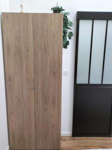 einem Holzschrank neben einer Tür mit Topfpflanze in der Unterkunft Studio - Au fond de la cour in Lacroix-Saint-Ouen