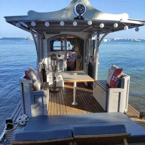 ein Boot mit einem Tisch und Stühlen auf dem Wasser in der Unterkunft Bateau logement nuit Insolite Astragale in Lège-Cap-Ferret