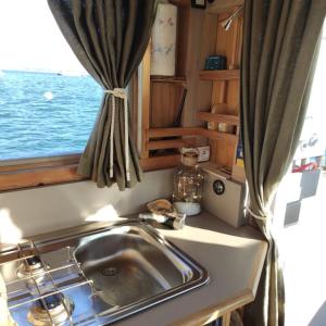 a kitchen counter with a sink and a window at Bateau logement nuit Insolite Astragale in Lège-Cap-Ferret