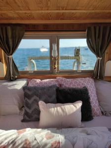 a bedroom with a bed with pillows and a window at Bateau logement nuit Insolite Astragale in Lège-Cap-Ferret
