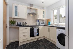 a kitchen with white cabinets and a washer and dryer at Host Liverpool - Spacious Home for Family & Groups in Liverpool