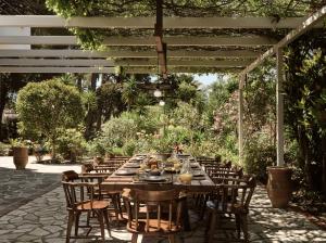 a long wooden table and chairs under a pergola at La Maison Du Maire Luxury Villa in Sarakinádhon