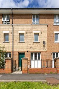 a brick building with a green door and a fence at Host Liverpool - Spacious Home for Family & Groups in Liverpool