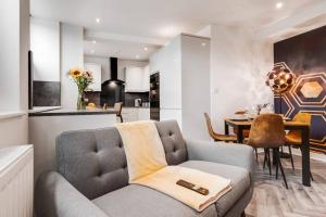 a living room with a gray couch and a kitchen at Victoria Stay - Parking Wi-Fi Amazing in Hyde