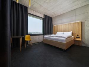 a bedroom with a bed and a desk and a window at Boulderbar Hotel Leonding in Linz