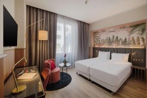 um quarto de hotel com uma cama branca e uma cadeira em NH Collection Milano Touring em Milão