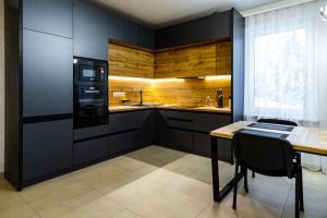 a kitchen with black cabinets and a table with chairs at Lidia chalets in Polyanitsa Popovichevskaya