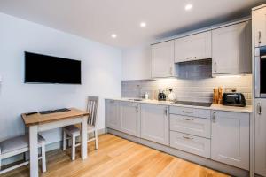 a kitchen with white cabinets and a wooden table at Hawkers Padstow in Padstow