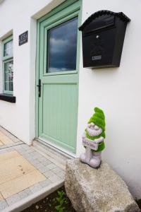 Un juguete de rana sentado en una roca delante de una puerta en No. 173 'Widow's Row', en Newcastle