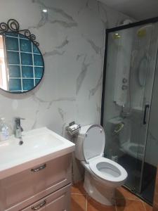 uma casa de banho com um WC, um chuveiro e um lavatório. em Barcelona Village Homestay em Tiana