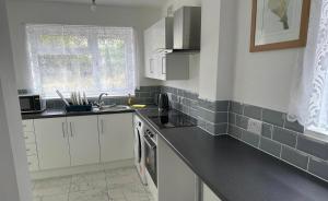 uma cozinha com armários brancos e um balcão preto em PUREWAYS em Southampton