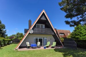 ein Haus mit einem dreieckigen Dach mit einem Tisch und Stühlen in der Unterkunft Ferienhaus Am Tief in Neuharlingersiel