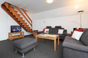 ein Wohnzimmer mit Sofas, einem TV und einer Treppe in der Unterkunft Ferienhaus Am Tief in Neuharlingersiel