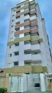 a tall white building with balconies on it at Ap da Tia in Praia Grande