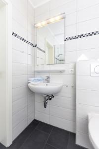 a white bathroom with a sink and a mirror at Ferienhaus Am Tief in Neuharlingersiel