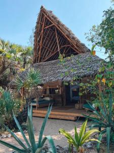 a hut with a thatched roof in a garden at Che Shale in Mambrui