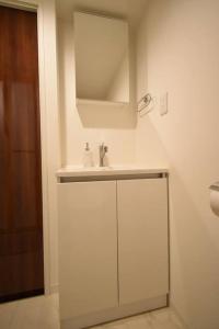 a white bathroom with a sink and a mirror at 東駒形302 in Tokyo