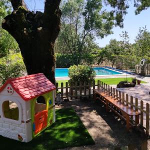 a toy dog house and a bench next to a tree at Casa Rural Viñas Perdidas in Béjar