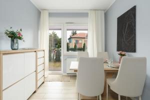 a dining room with a table and white chairs at Apartment with garden Wolkowyska by Renters in Poznań