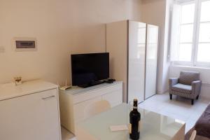 ein Wohnzimmer mit einem TV und einer Flasche Wein in der Unterkunft SPQR Studios 2 Valletta in Valletta