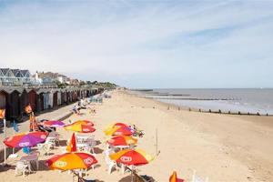 a beach with many umbrellas and chairs and the ocean at Julie'scaravan lettings in Kirby Cross