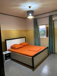a bedroom with a bed with orange sheets and a window at Your Home III in Yaoundé