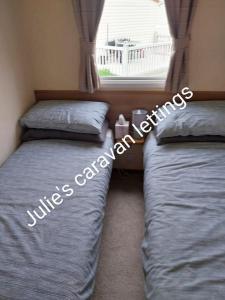 two twin beds in a room with a window at Julie'scaravan lettings in Kirby Cross