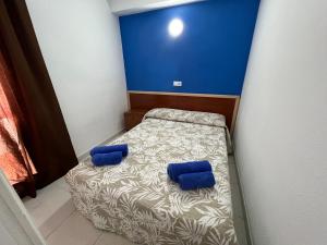 1 cama pequeña con almohadas azules en una habitación pequeña en Apartaments Monjardí en Lloret de Mar
