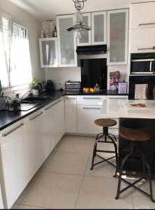 a kitchen with white cabinets and two bar stools at SGDB in Sainte-Geneviève-des-Bois