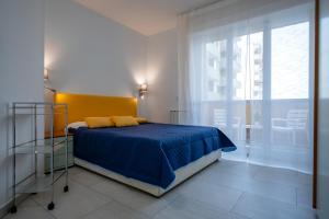 a bedroom with a bed with blue sheets and a window at Kalbia Apartment Renovated, functional, intimate and more in Cagliari