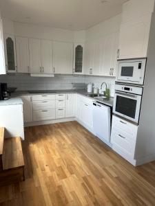 cocina blanca con electrodomésticos blancos y suelo de madera en RFM Tingsryd, en Tingsryd