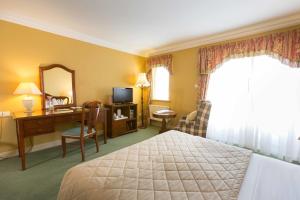 a hotel room with a bed and a desk and a mirror at Sheedys Boutique Hotel & Restaurant in Lisdoonvarna