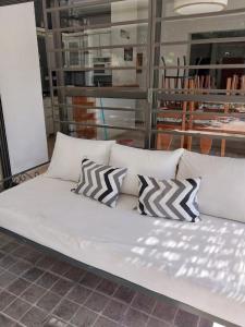 Un sofá blanco con tres almohadas. en Casa Ayacucho en Villa Carlos Paz