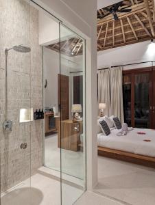 a bedroom with a bed and a glass shower at Umarato Villa Sumba in Rua