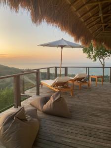 eine Terrasse mit Tisch, Stühlen und Sonnenschirm in der Unterkunft Umarato Villa Sumba in Rua