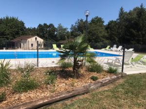 una valla alrededor de una piscina con palmeras en Gîtes à la campagne 