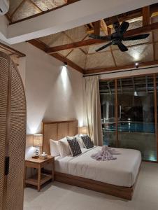 Umarato Villa Sumba في Rua: غرفة نوم بسرير ومروحة سقف