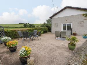 eine Terrasse mit Stühlen, einem Tisch und Blumen in der Unterkunft Bide-a-While in Marnoch